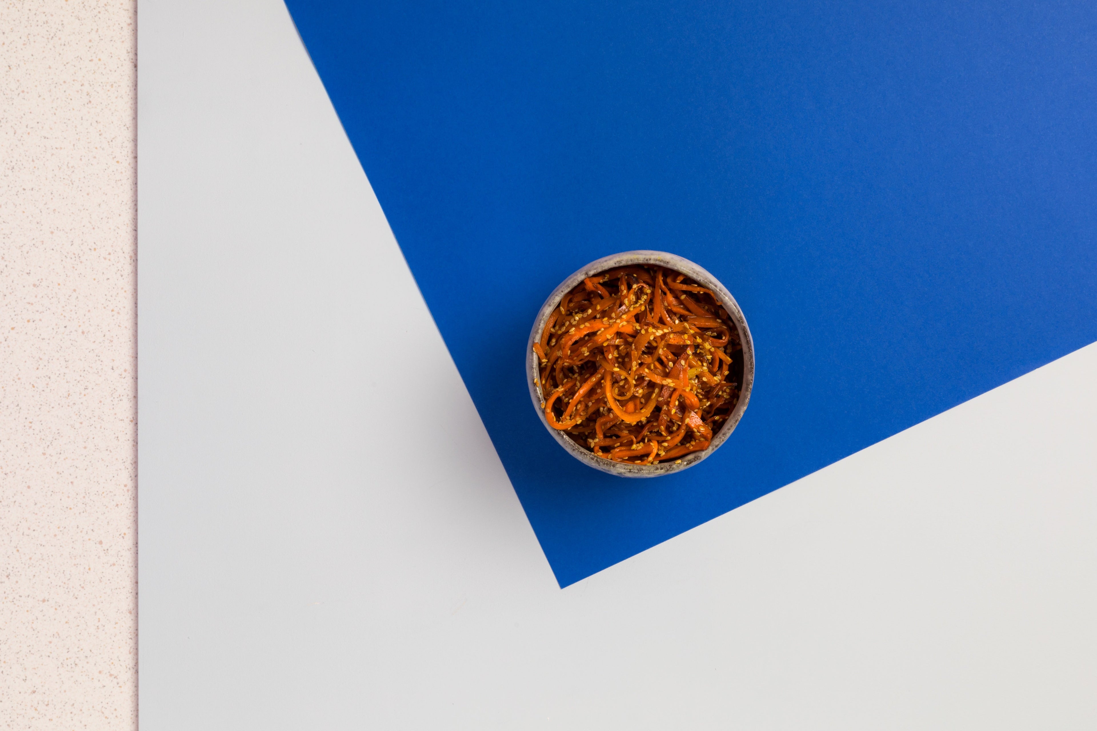 A vibrant bowl of shredded carrot, sesame seeds, chilli and honey.